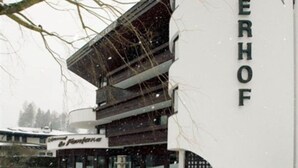 Un bâtiment moderne dont la façade porte l’inscription « ROMERHOF », caractérisé par une structure à plusieurs niveaux et un espace extérieur visible, agrémenté d’une fontaine.