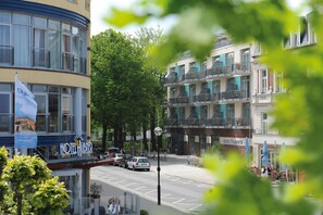 Un hotel con fachada moderna, varios balcones y vistas a la calle con coches estacionados.