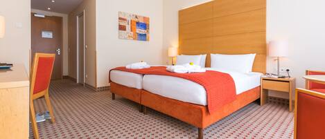 A hotel room with a large bed, two bedside tables, a desk, and a chair.
