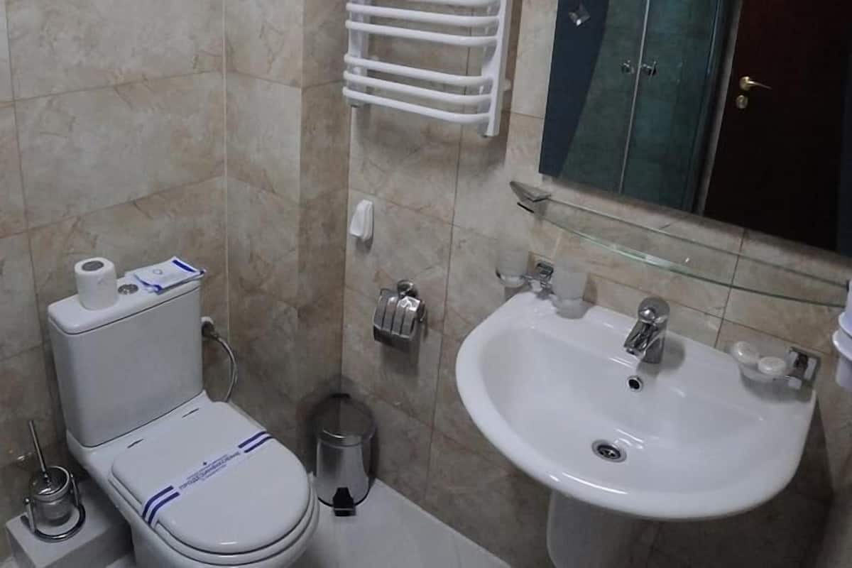 A bathroom with a toilet, sink, and a glass shower enclosure.