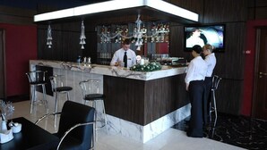 A bar area with a marble countertop, bar stools, and a television screen. - Mir Hotel In Rovno (Rivne)