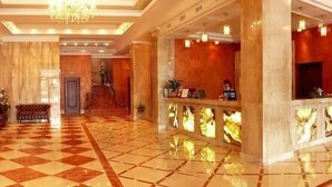 A lobby with a checkered floor, a reception desk, a staircase, and a seating area with a sofa and chairs. - Mir Hotel In Rovno (Rivne)
