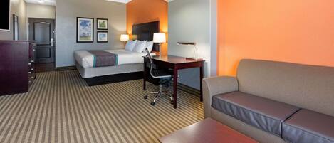 A hotel room with a bed, a desk, a sofa, and a TV.