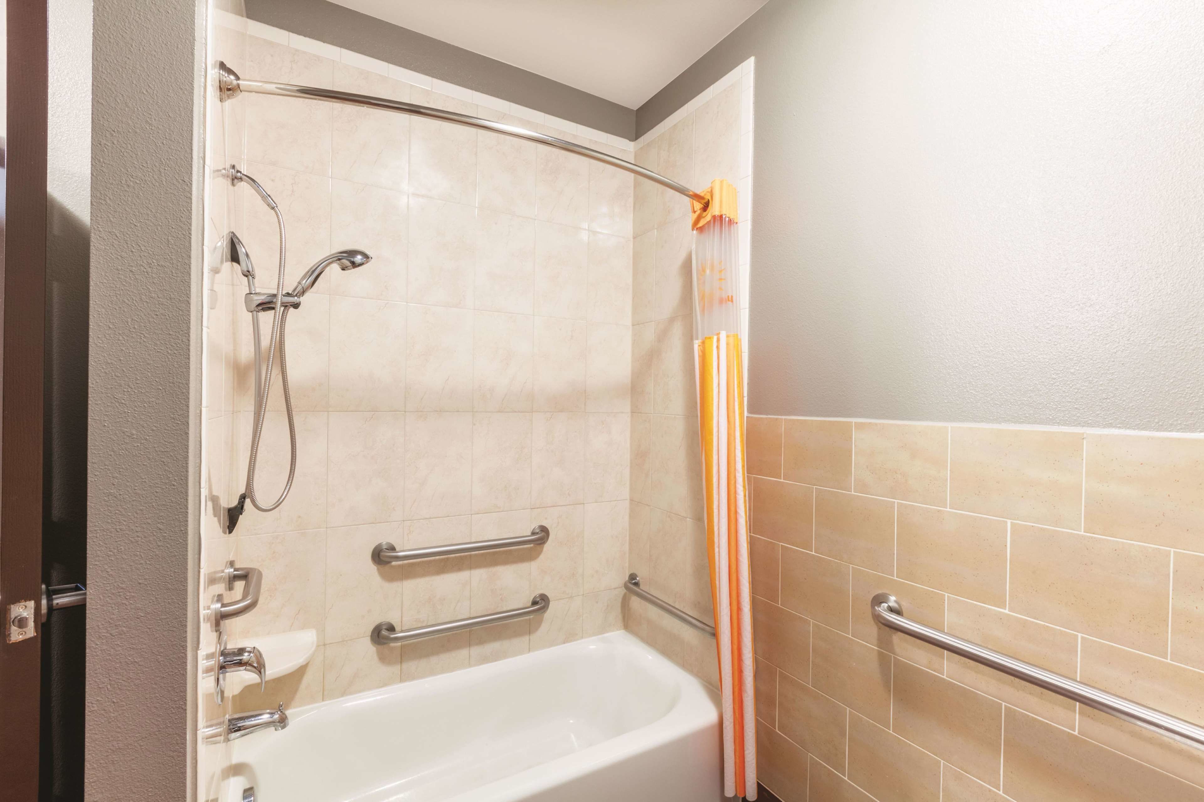 Bagno con vasca, doccia e maniglie di sostegno.