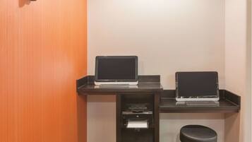 A small office area with two laptops on desks, a printer, and a waste basket.