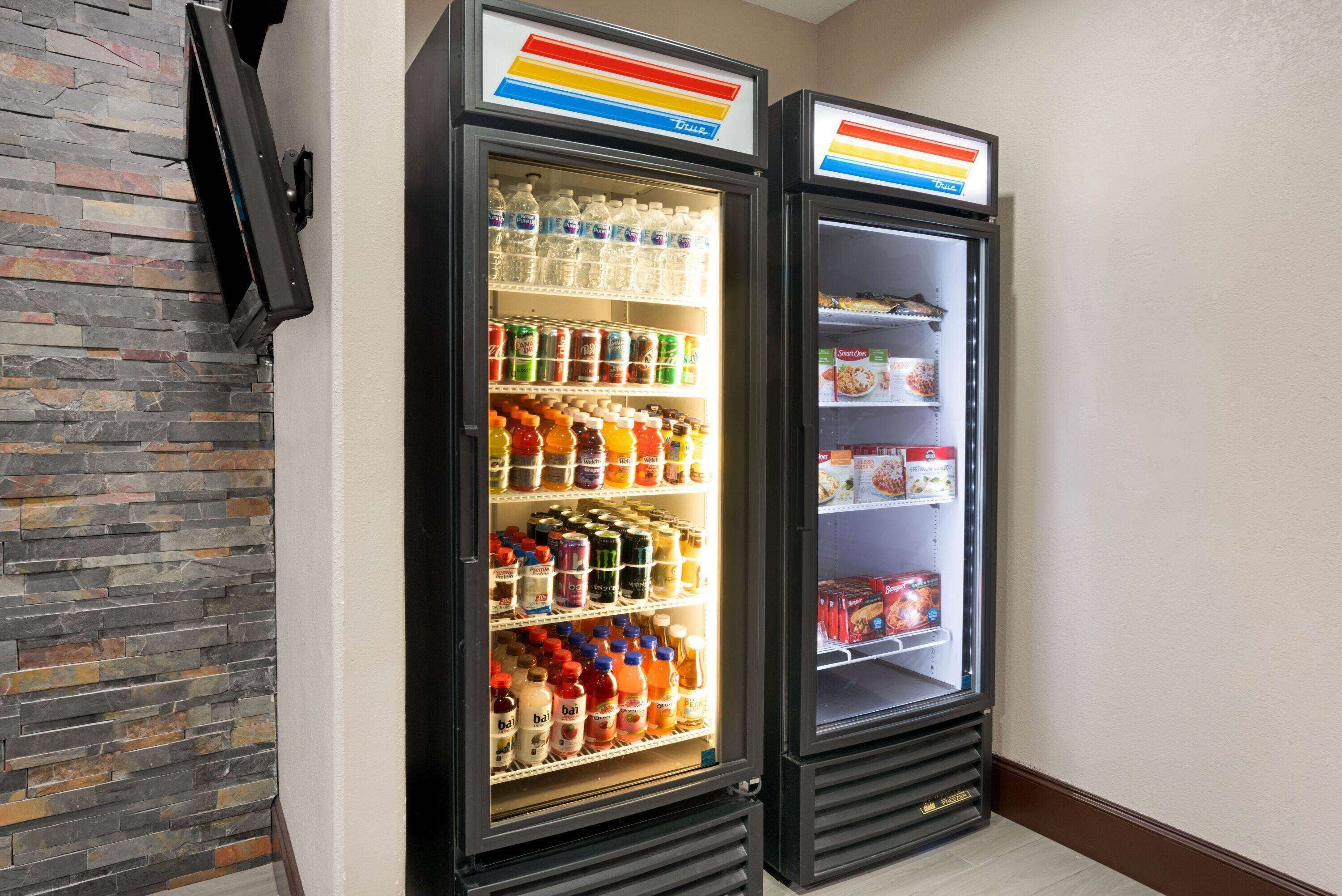 Two beverage dispensers stocked with various drinks and snacks, mounted on a wall with a stone-like texture.