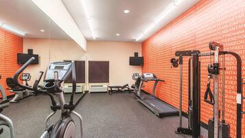 Un gimnasio con equipo cardiovascular, máquinas de pesas y un espejo grande.