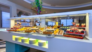A buffet with various desserts and a large plant in the center. - Cesar Thalasso (Djerba Midun)