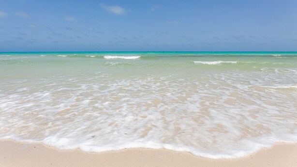 A beach with clear turquoise water and gentle waves. - Cesar Thalasso (Djerba Midun)