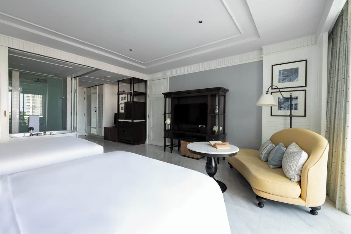 Ett modernt hotellrum med en stor säng, en soffa, en TV och ett matbord.