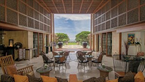 An indoor seating area with tables and chairs, a view of a garden, and a decorative ceiling. - Intercontinental Hua Hin Resort by IHG (Hua Hin)