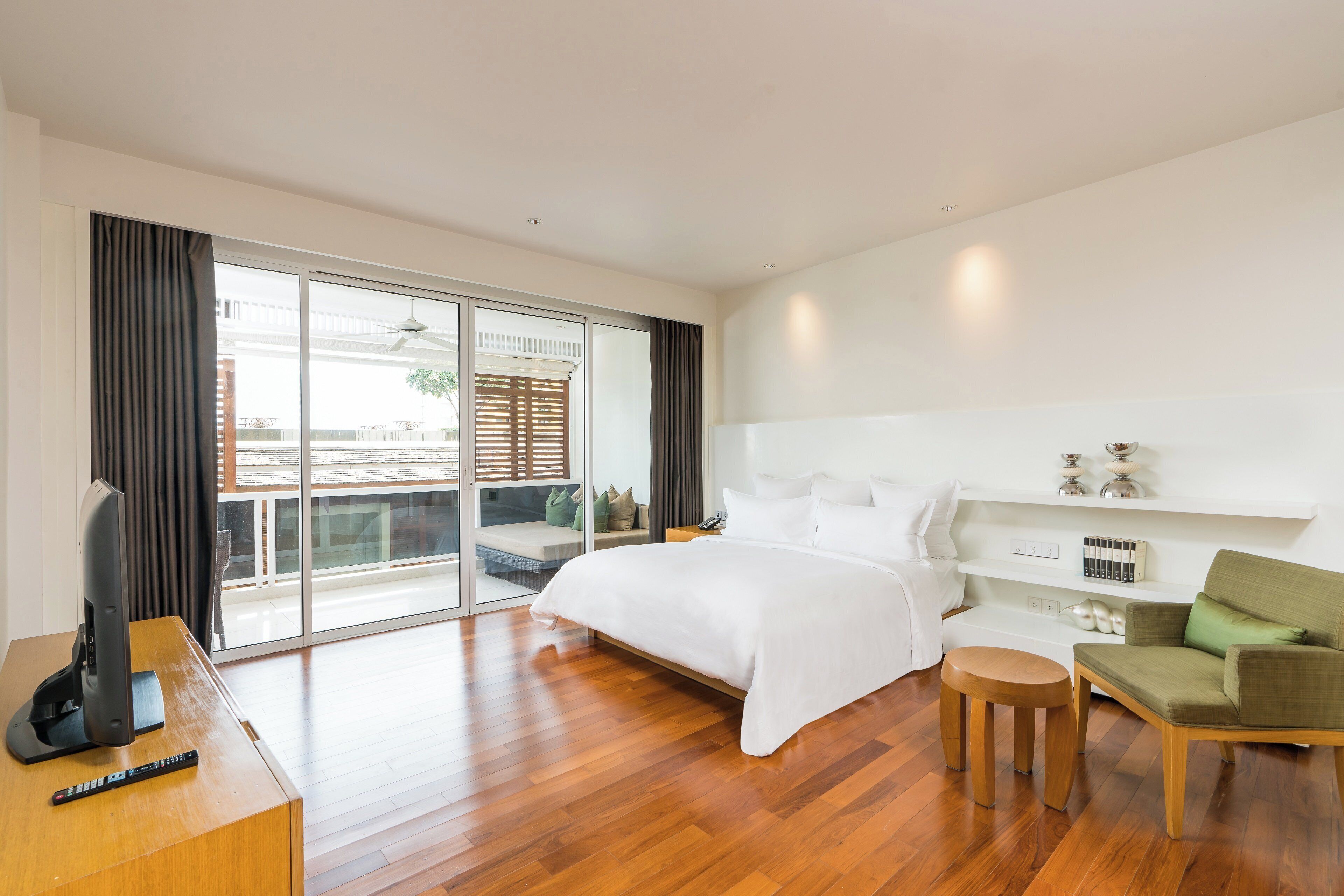 Een moderne hotelkamer met een groot bed, een televisie, een bureau en een balkon met uitzicht.
