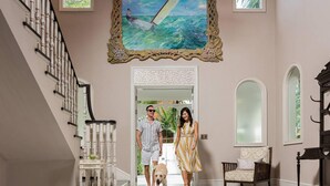 A grand entrance with a staircase, a framed painting, and a dog.