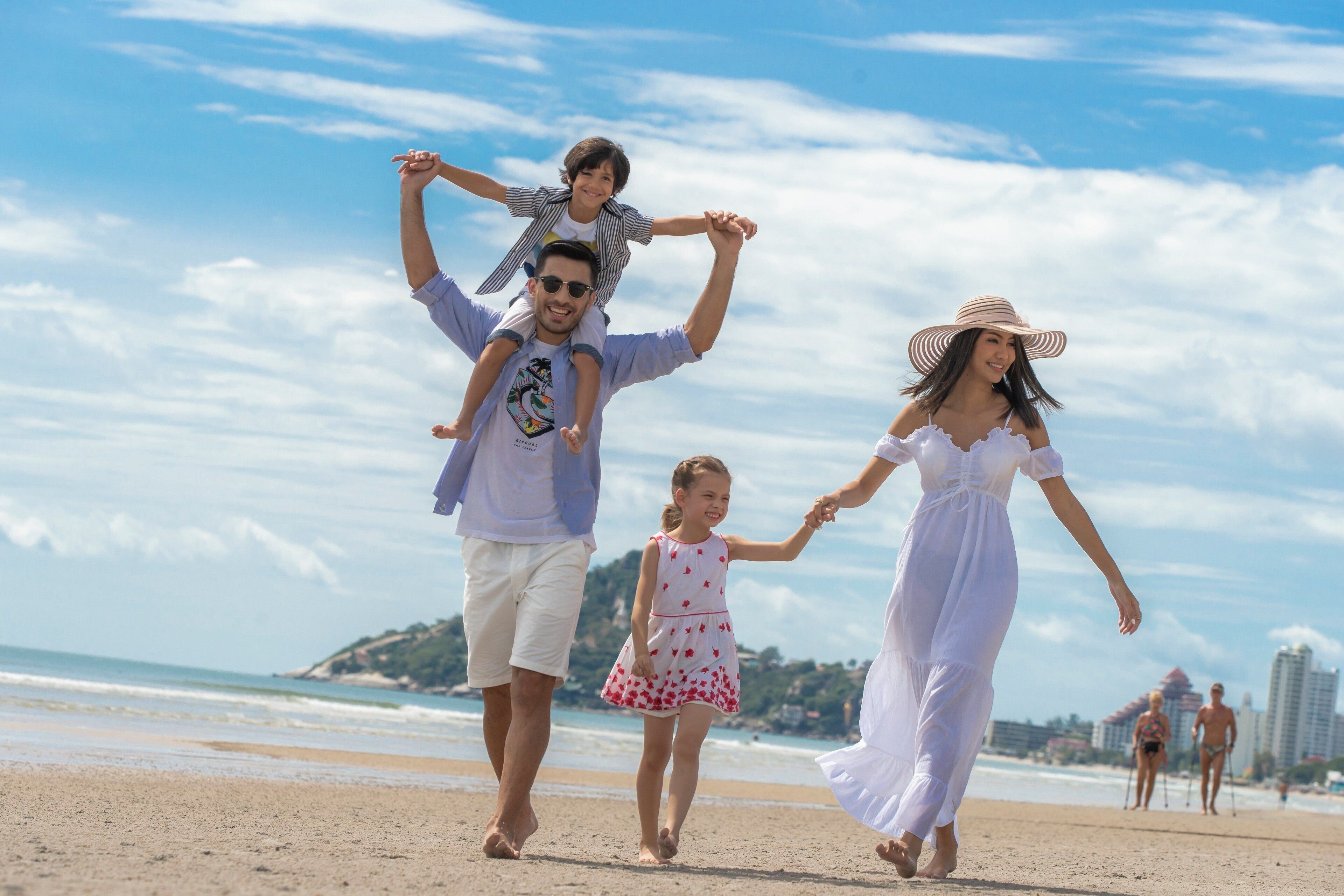 A family walking on a beach with clear skies.