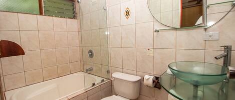 Une salle de bain avec une douche à parois de verre, un lavabo en verre et des toilettes.