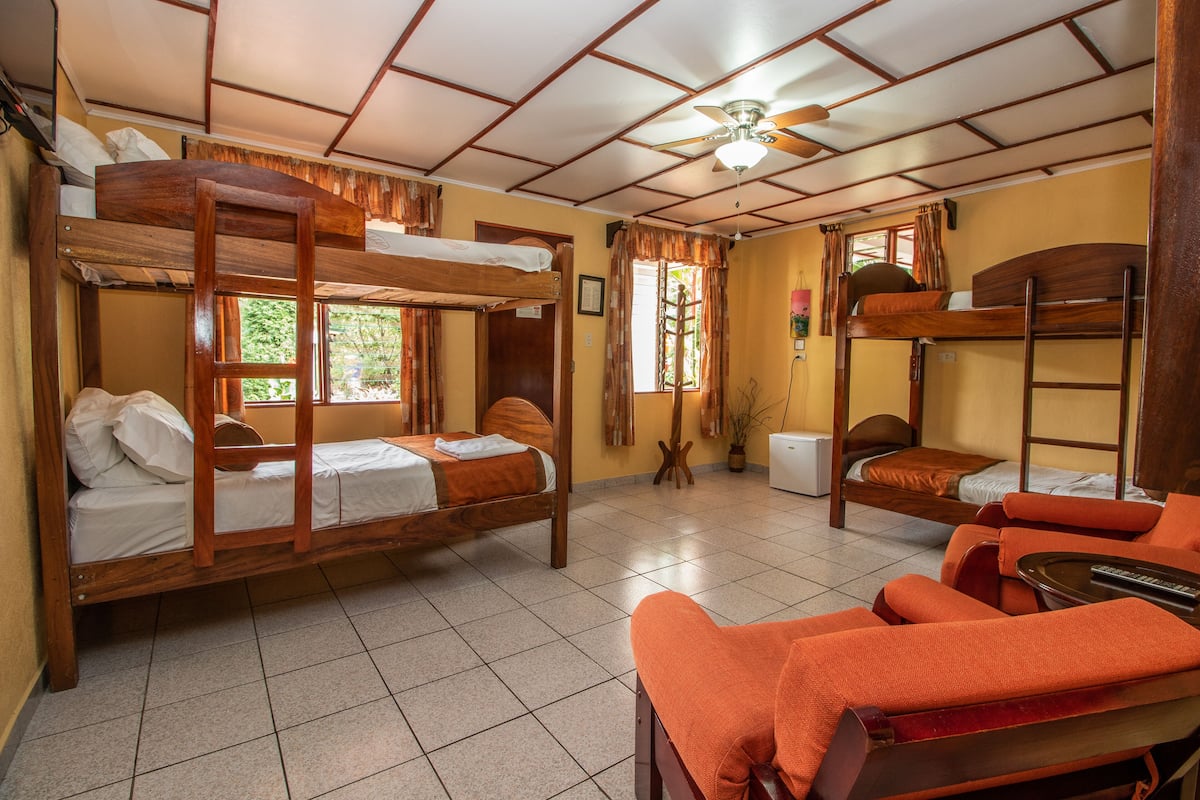 A dormitory room with bunk beds, a ceiling fan, and a small table.