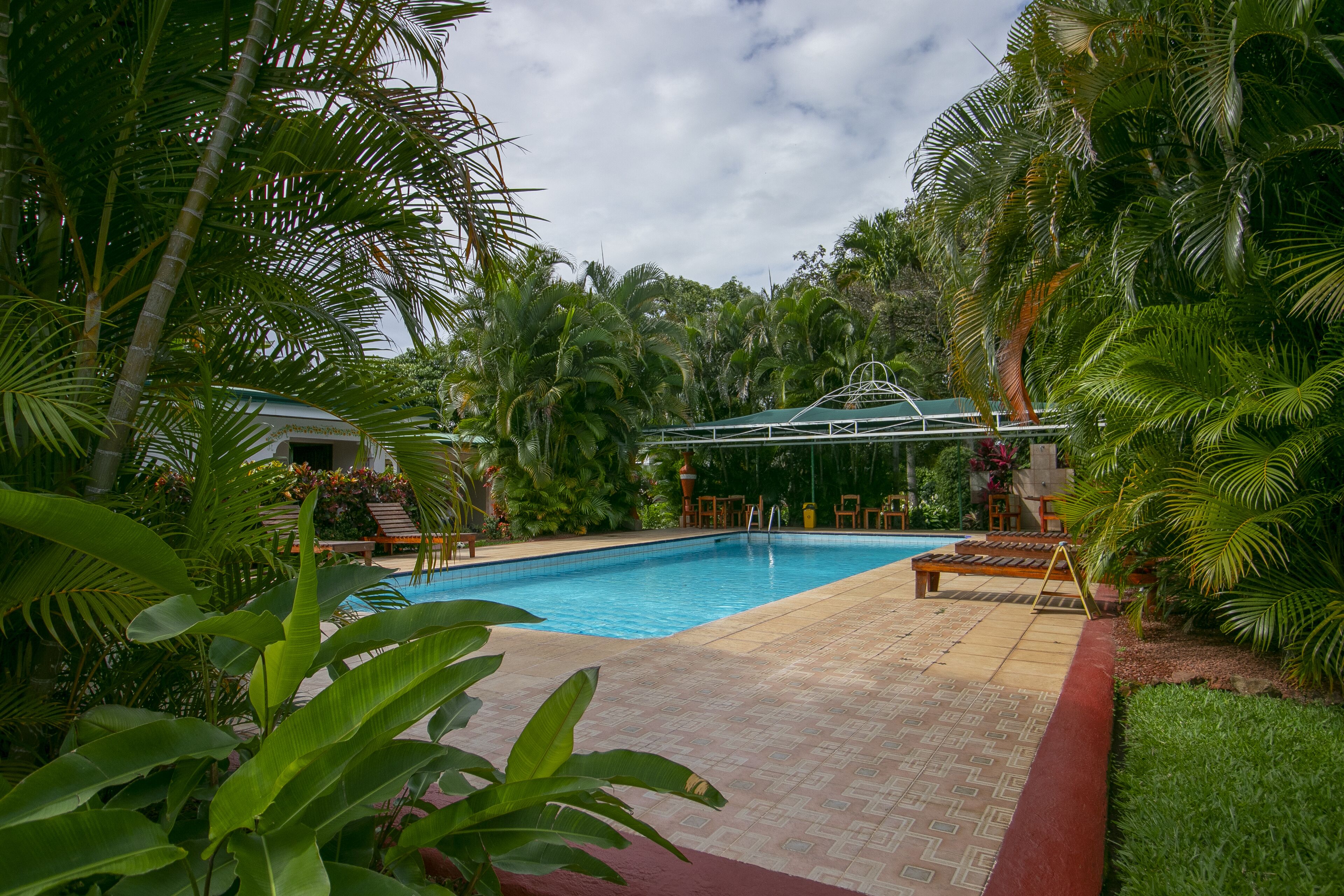Piscina rodeada por vegetação exuberante e palmeiras.