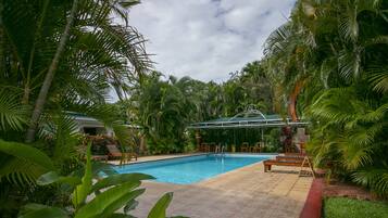 Piscina rodeada por vegetação exuberante e palmeiras.