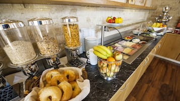 Un bufé con diversos alimentos, entre ellos frutas, verduras y productos horneados.
