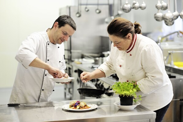 Deux chefs travaillent dans une cuisine professionnelle et préparent des plats.
