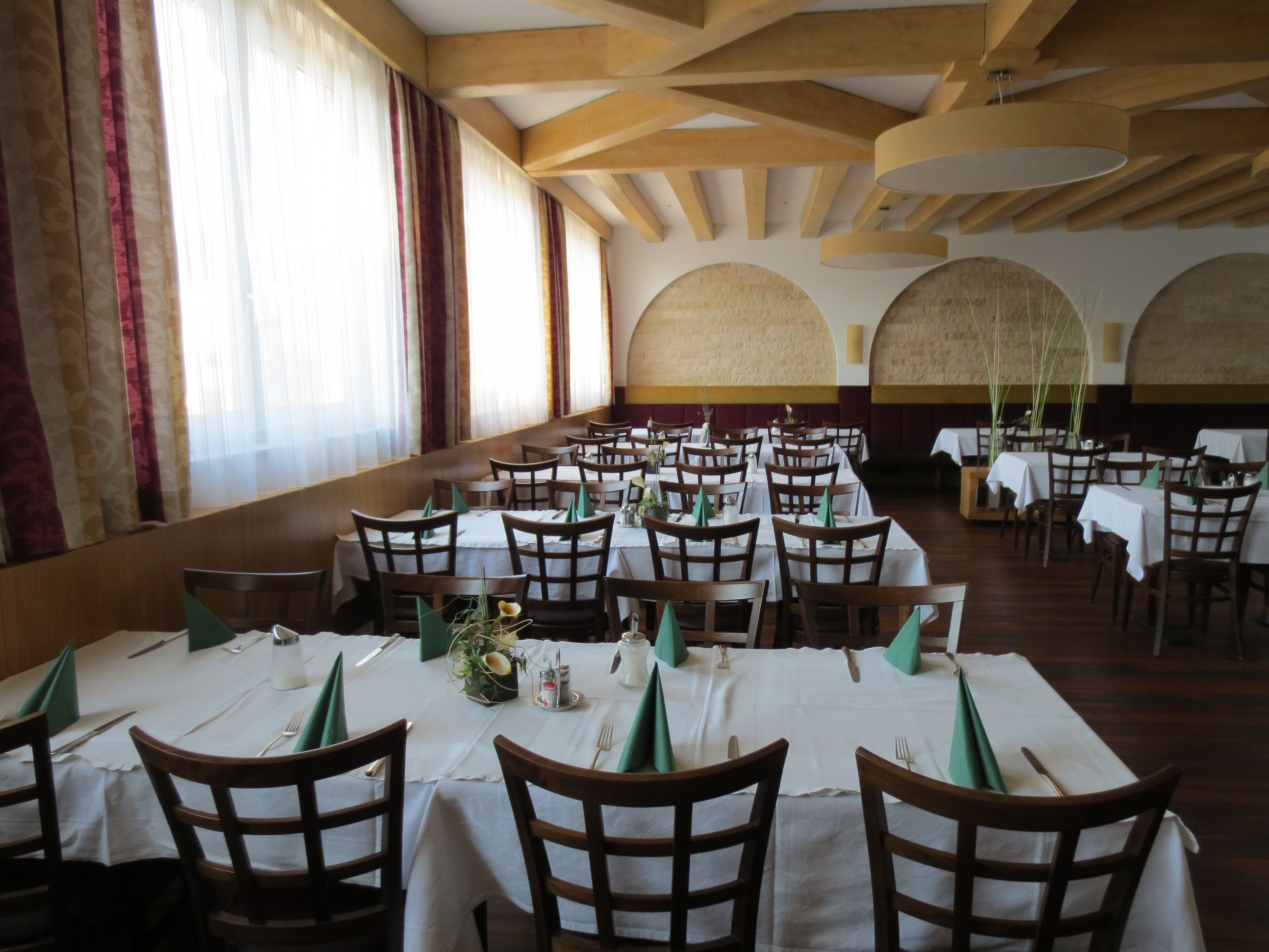A large dining hall with multiple tables and chairs, arranged in rows.