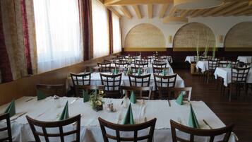 A large dining hall with multiple tables and chairs, arranged in rows.