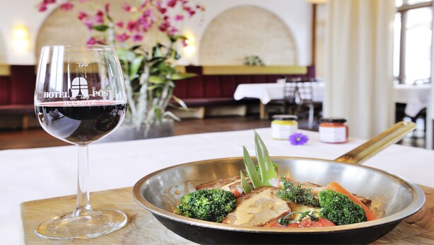 Une table à manger avec un verre de vin rouge et un plat de nourriture.