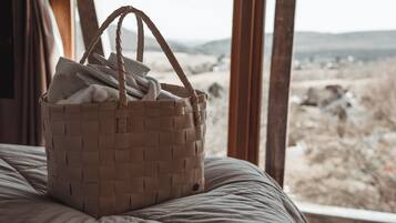 A wicker basket on a bed with a view of a rocky landscape through a window.