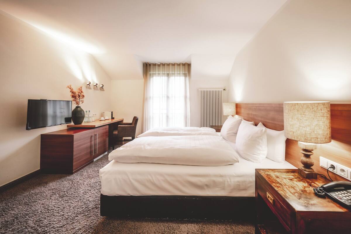 A hotel room with a bed, a desk, a television, and a lamp.