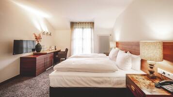 Ein Hotelzimmer mit Bett, Schreibtisch, Fernseher und Lampe.