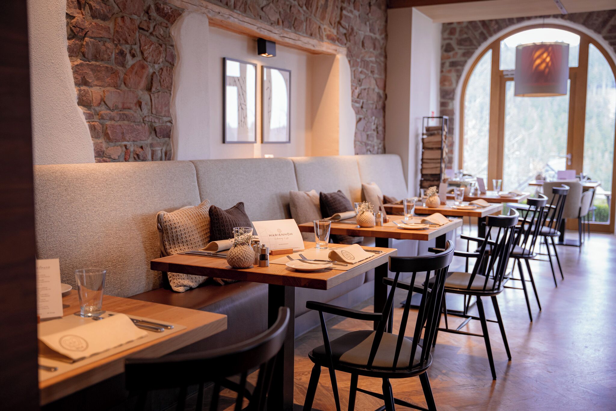 Un restaurant amb parets de pedra, taules de fusta i cadires negres.