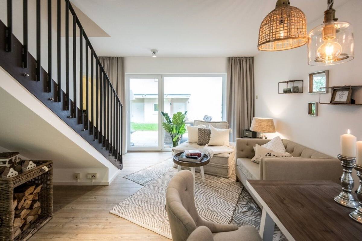 A modern living room with a staircase, a sofa set, a coffee table, and a dining table.