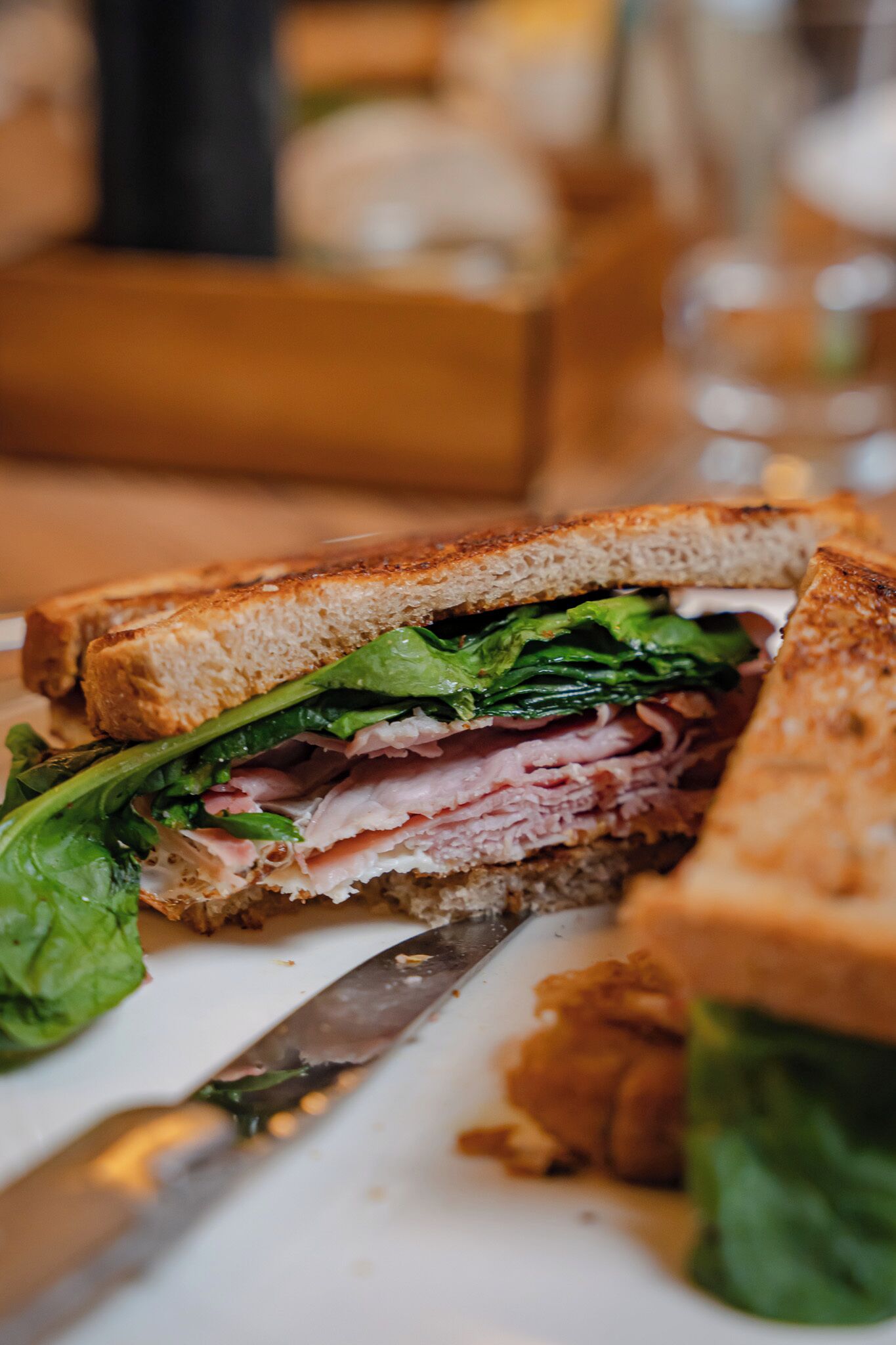 A sandwich with visible layers of lettuce, meat, and bread on a white plate.