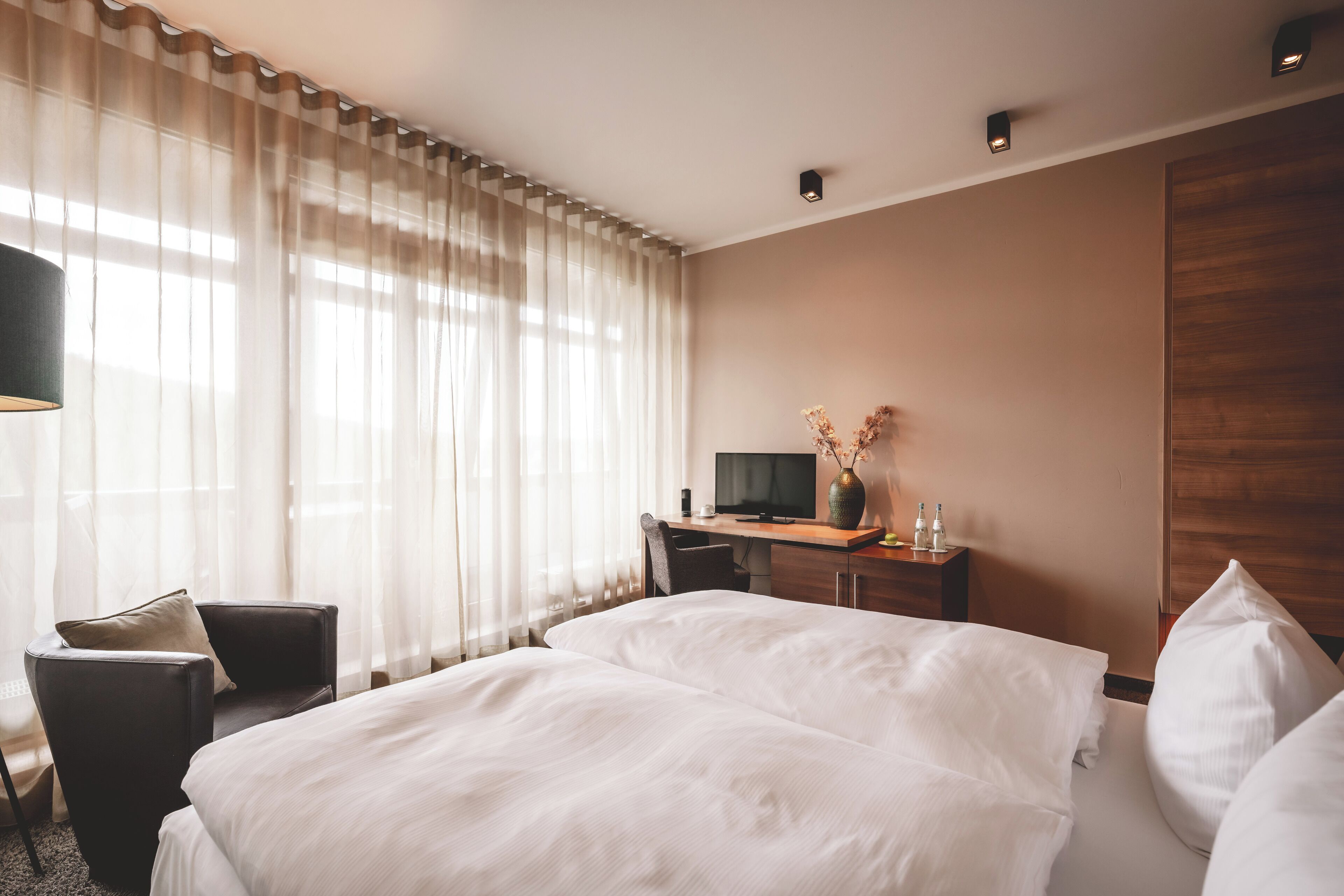 Une chambre d’hôtel avec un lit, un bureau avec un ordinateur, une chaise et un téléviseur.