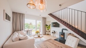 A modern living room with a sofa, a wooden dining table, and a staircase leading to an upper floor.