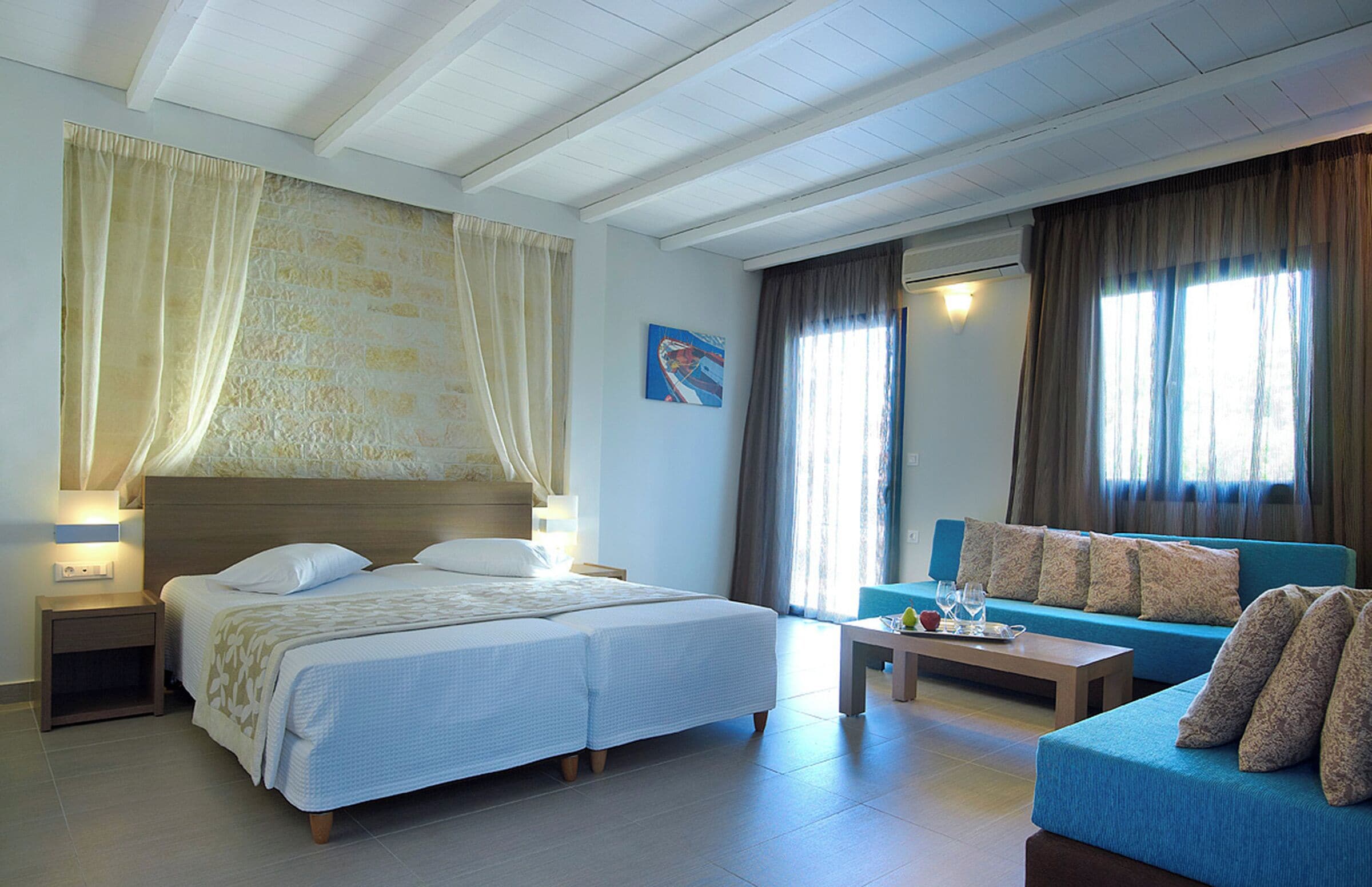 Une chambre d’hôtel avec un lit double, un canapé, une table basse et une petite table avec une lampe.