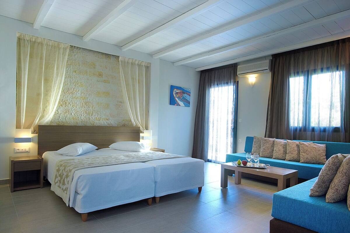 Una habitación de hotel con una cama doble, un sofá, una mesita de café y una mesita de noche con una lámpara.