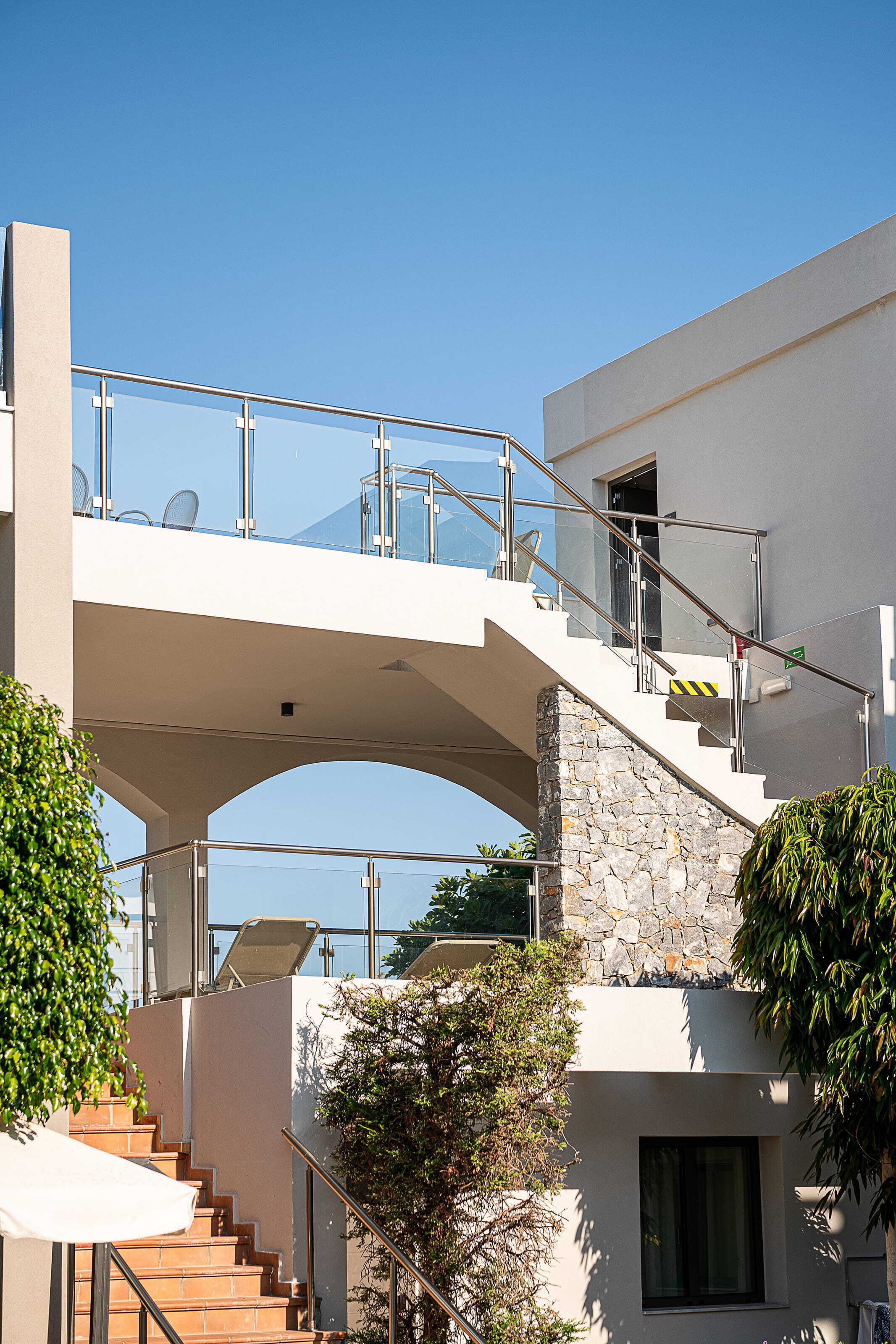 A modern building with a stone staircase and a glass bridge connecting two levels.