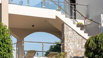 Un edificio moderno con una escalera de piedra y un puente de cristal que conecta dos niveles.