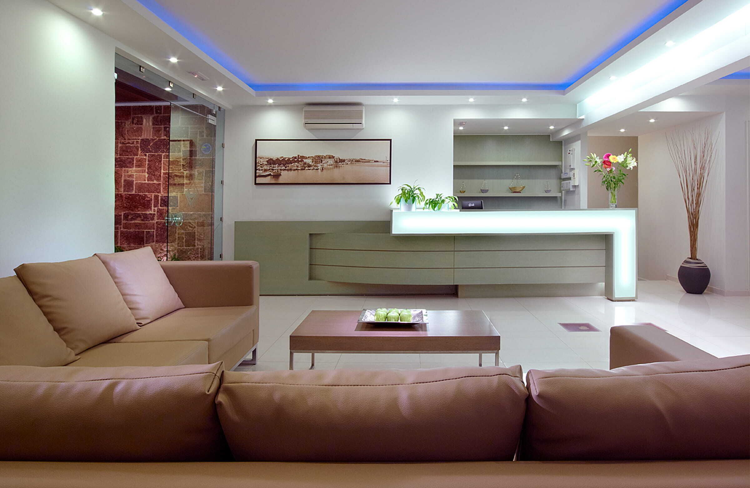A modern living room with a sofa, a coffee table, and a kitchen area with a counter and plants.