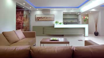 A modern living room with a sofa, a coffee table, and a kitchen area with a counter and plants.