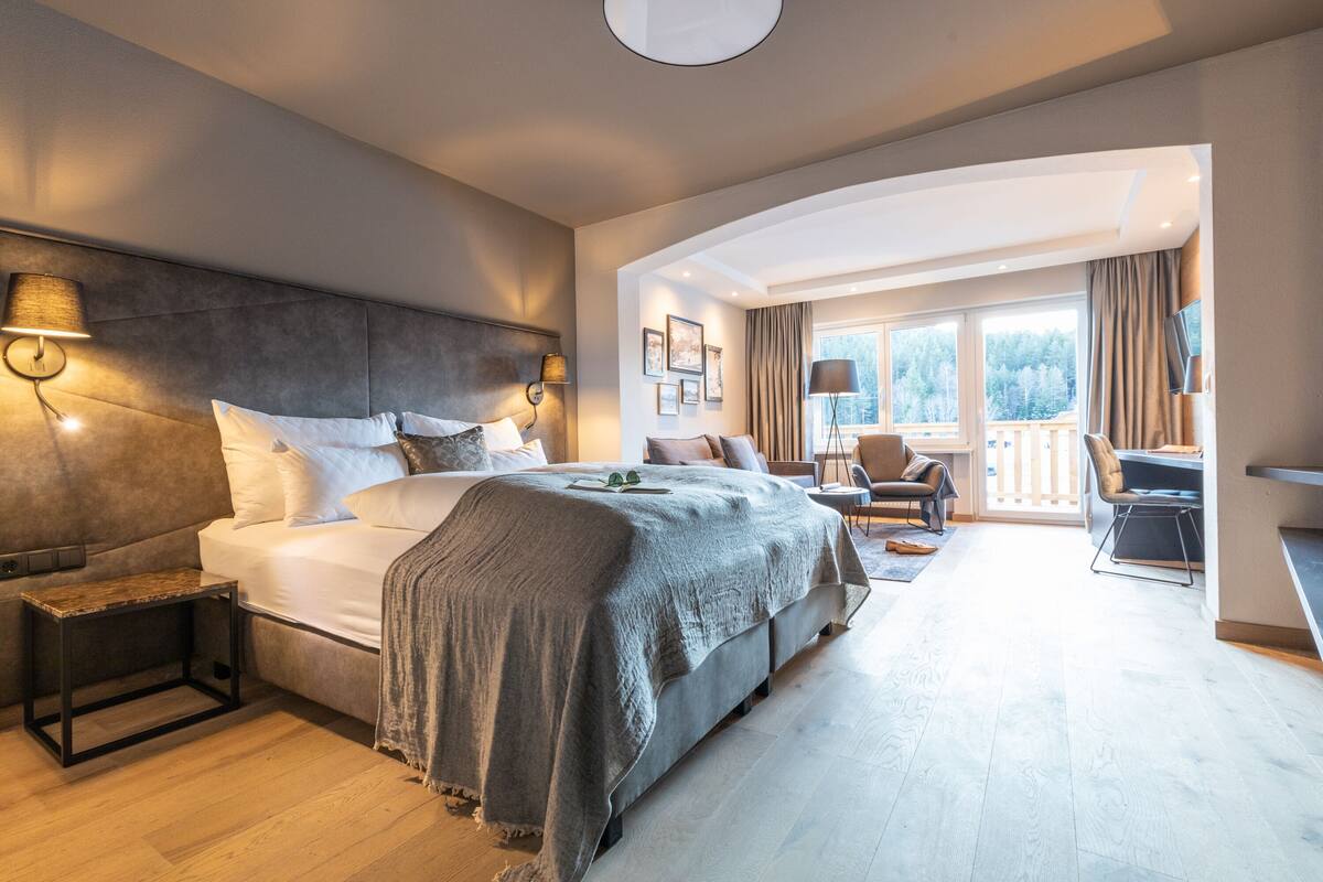 Ein modernes Hotelzimmer mit einem großen Bett, einem Schreibtisch und Blick ins Freie.