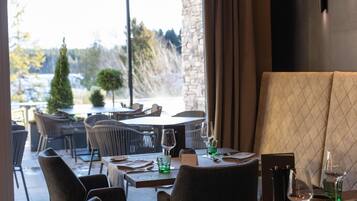 Un restaurante con terraza, paredes de piedra y vistas a árboles y un edificio.
