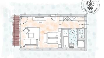 Un plan d’étage d’une chambre d’hôtel comprenant un lit, un bureau, une chaise, une petite salle de bain et un coin cuisine.