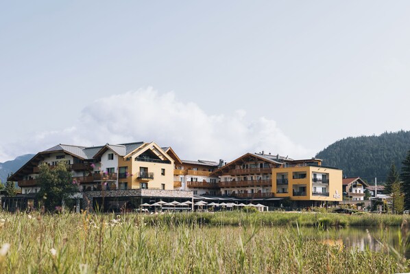 Un hotel con varios pisos, asientos al aire libre y vistas a un lago.