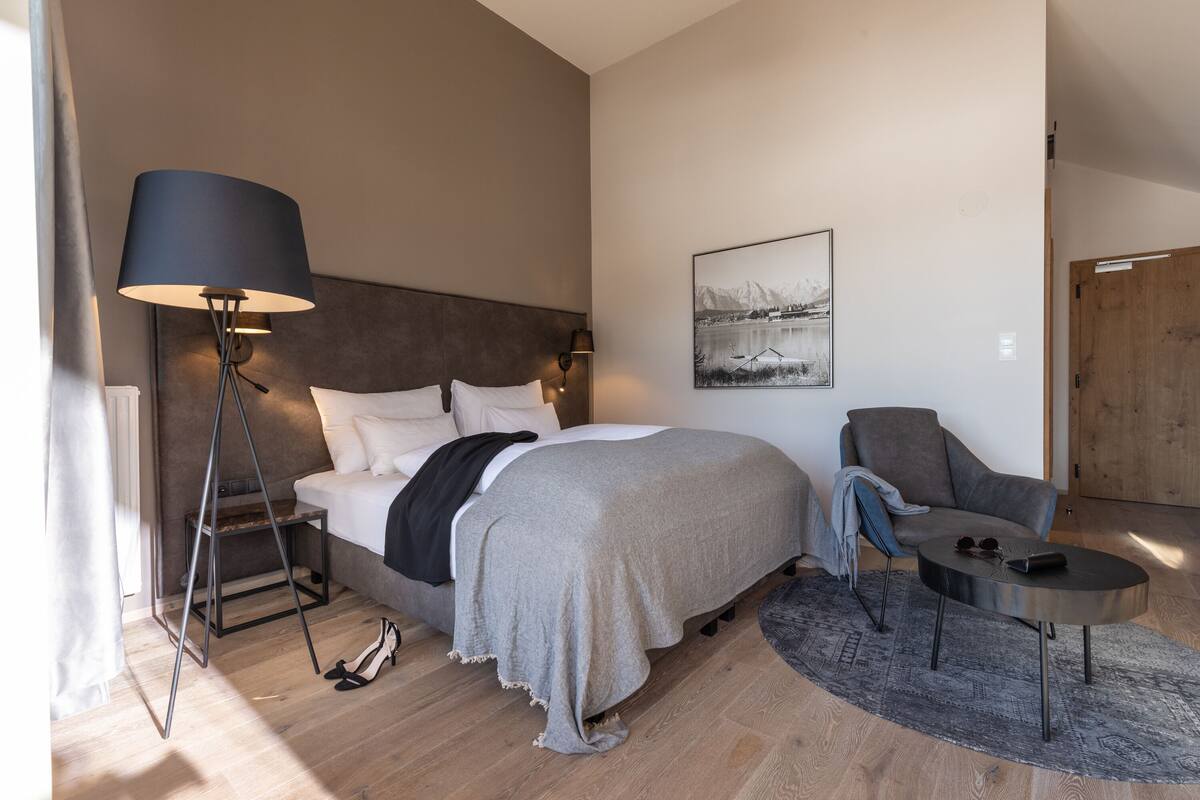Ein modernes Schlafzimmer mit Bett, Nachttischlampe, Stuhl und kleinem Tisch.