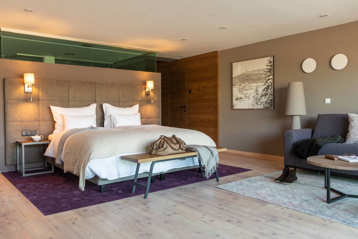 Ein modernes Hotelzimmer mit einem großen Bett, Nachttischen, einer Bank, einem Sofa und einem Couchtisch.