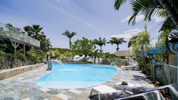 Ein Pool mit Liegestühlen und Palmen.