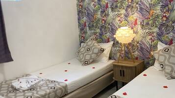 Une chambre d’hôtel avec deux lits simples, un mur décoré de motifs, une lampe de chevet et une fenêtre.