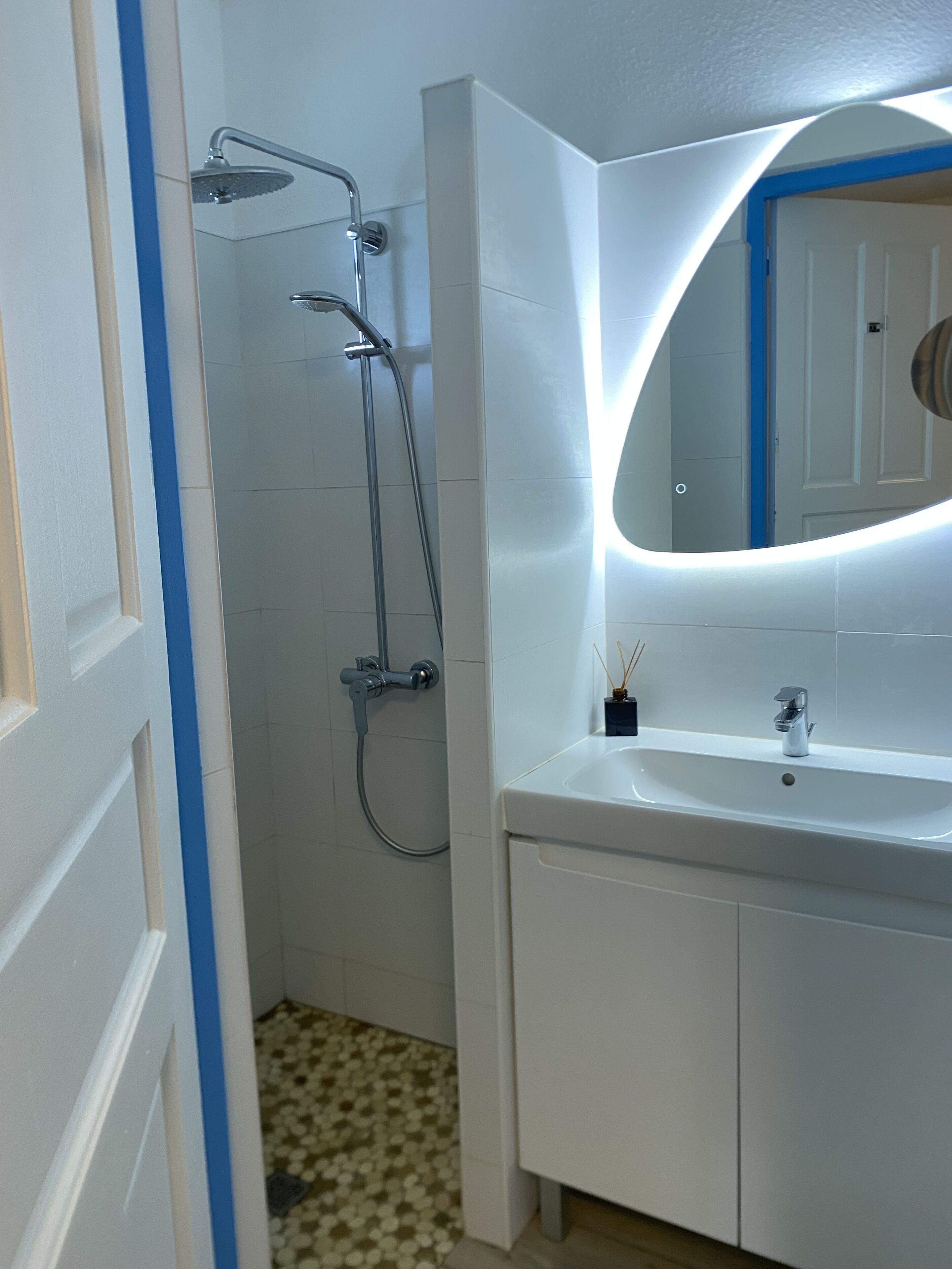 Une salle de bain avec une douche, un lavabo et un miroir.